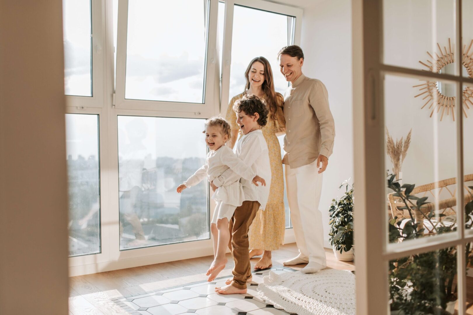 Happy family of four enjoying a sunny day by large windows.